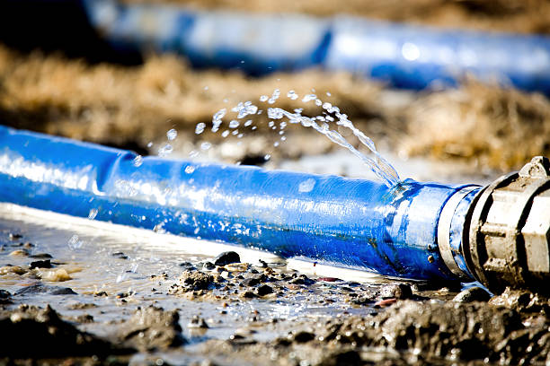 A blue water hose leaking water from a hole stock photo