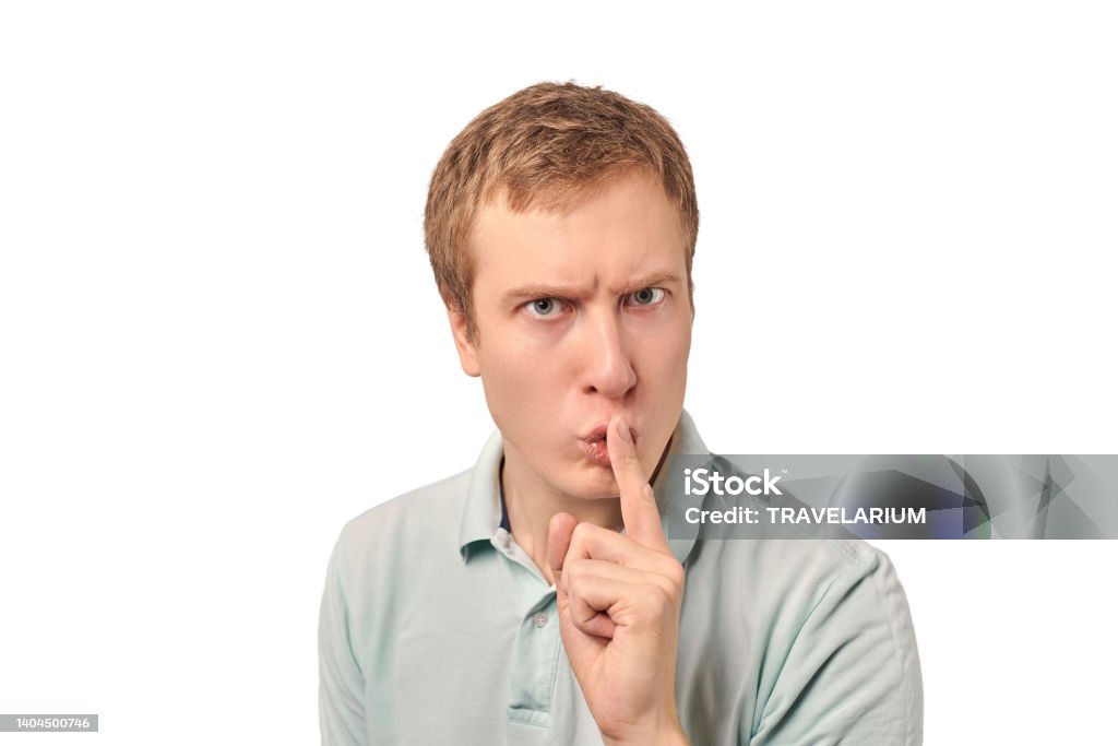 Funny guy in light gray Polo T-shirt asking to be quiet, silence gesture, white background Funny guy in light gray Polo T-shirt asking to be quiet, silence gesture isolated on white background. Young man saying Shhh, keep quiet, please and making silence gesture, request for silence Adult Stock Photo