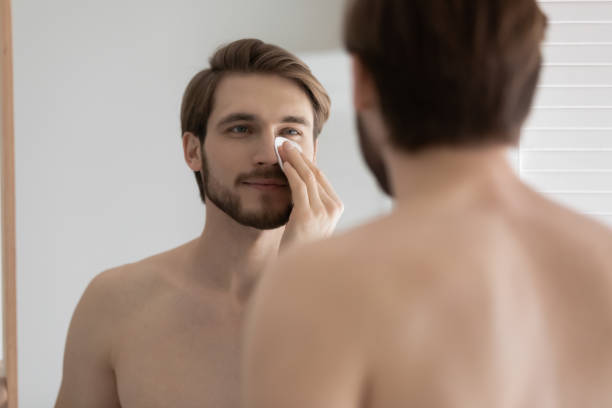 istock Man holding cotton pad cleaning face with tonic 1404501457