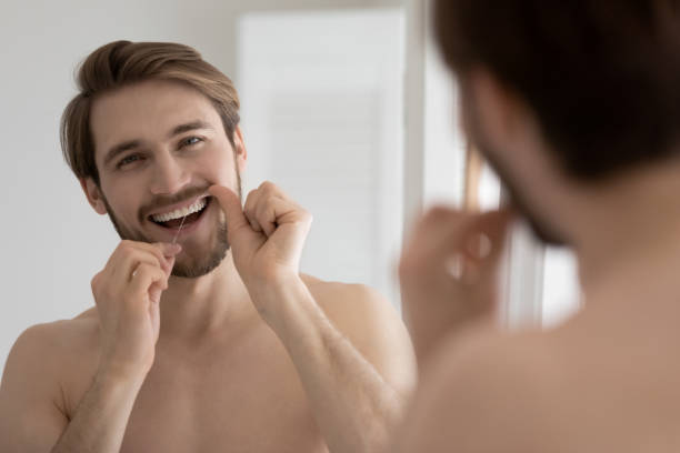 istock Handsome smiling guy cleaning teeth with dental floss 1404501770
