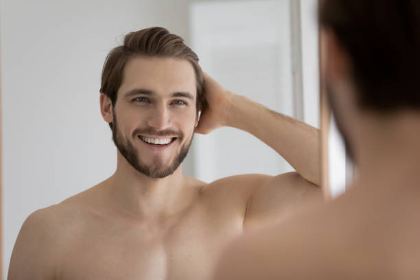istock Handsome shirtless man admires his reflection in mirror 1404502148