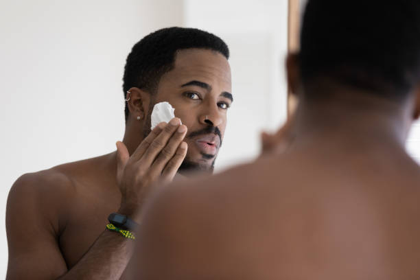istock African man looking in mirror applying shaving foam on face 1404502155