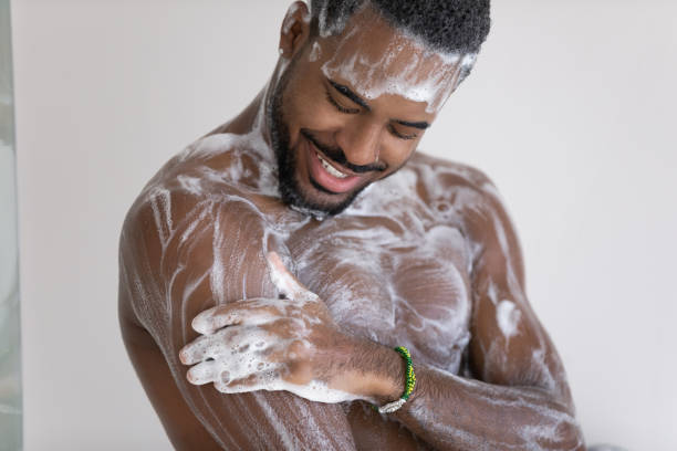 l'uomo africano fa la doccia lava il suo corpo con il sapone - men smooth the human body moisturizer foto e immagini stock