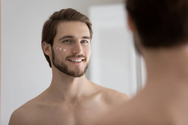 istock Man stand in front of mirror with applied face cream 1404503860
