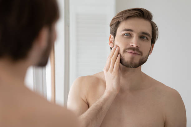 istock Young handsome man looking in mirror touch face 1404503882