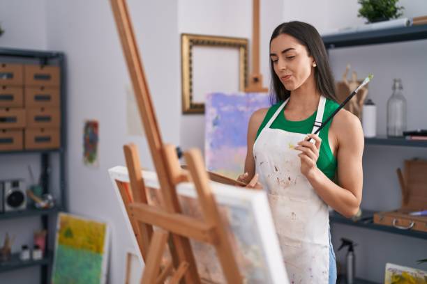 istock Young hispanic woman artist with doubt expression drawing at art studio 1404505328