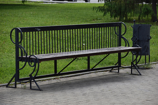 A large wooden bench in the city park in summer