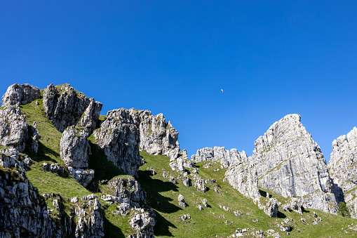 beautiful Italian Dolomites mountains with paraglider flying in the blue sky