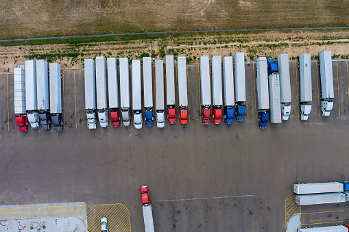 Trucks stand in a row at the rest area on the highway in aerial top view