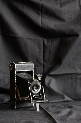 Very old photo camera against nice dark cloth background with free space
