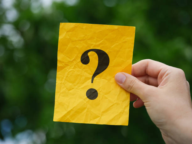 istock A woman holding a yellow note paper with a question mark on it in her hand over a background of foliage 1404513368