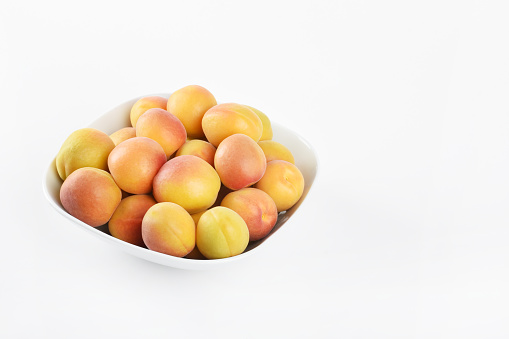 Apricots in a bowl on the white background with copy space