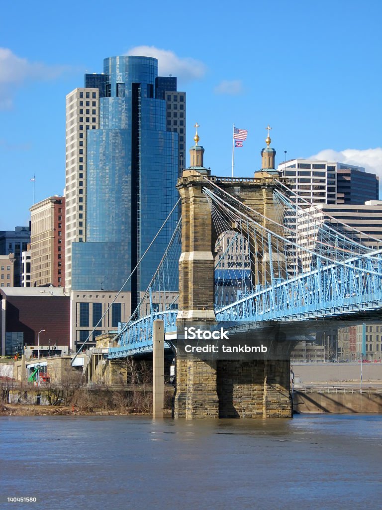 Photograph of a blue Roebling Suspension Bridge The John A. Roebling Suspension bridge and buildings in downtown Cincinnati, Ohio. Architecture Stock Photo