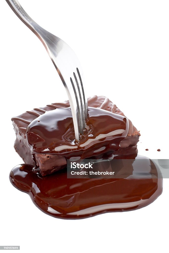 Fork pricking chocolate The fork pricking a chocolate cake with syrup on white background Addiction Stock Photo