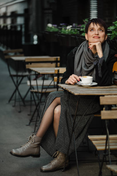 istock young woman sits at street cafe table drinking coffee 1404516759