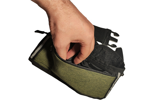 Man's hand opens an empty small sports waist bag isolated on white background