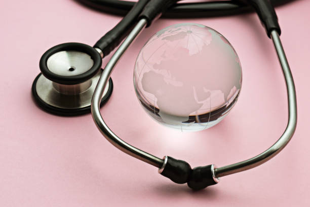 Glass globe and stethoscope on pink background.