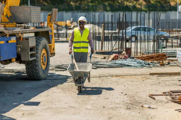 Photo of Construction worker pushing barrow at building site