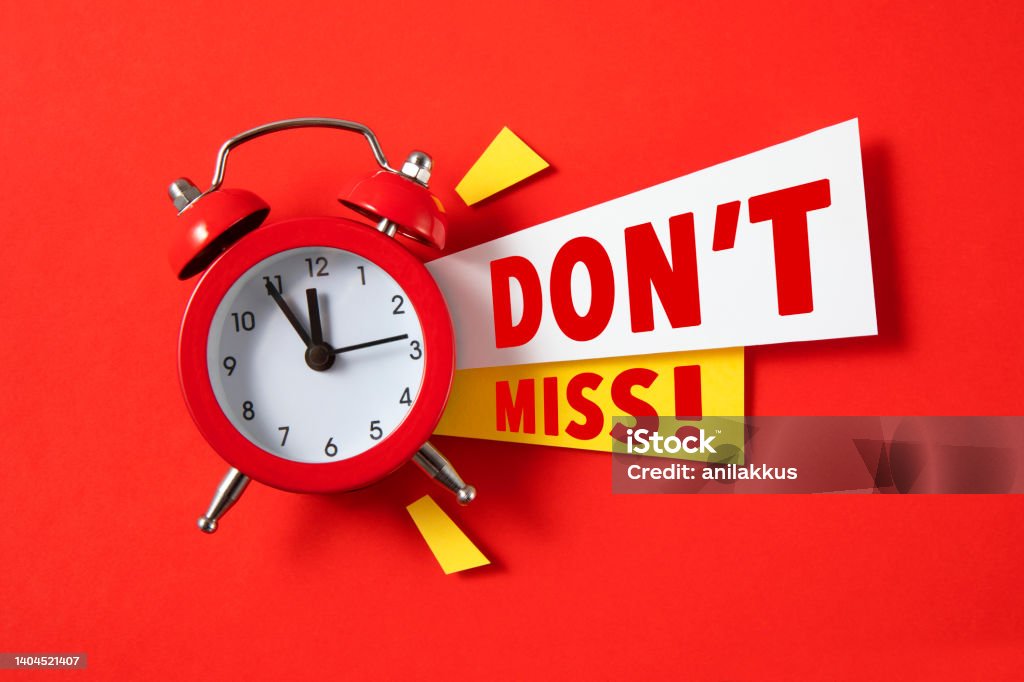 Don't Miss Red alarm clock with colored papers and do not miss text on red background Sale Stock Photo