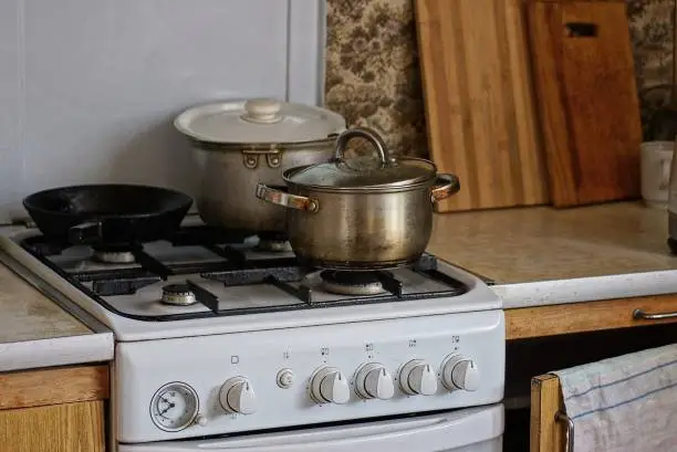 white gas stove with gray pots and a black frying pan at the table in the kitchen