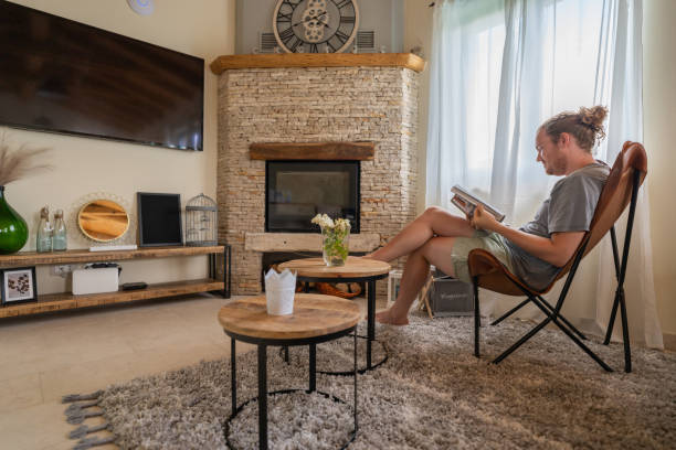 istock Young man relaxes in living room, reads book 1404524518