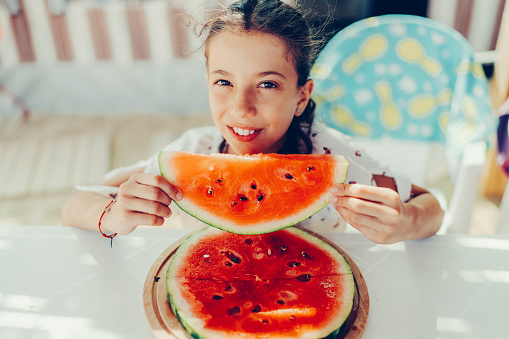 Cute portrait of girl eating watermelon on hot summer day