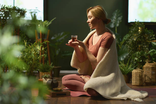 モダンな緑の家でお茶を飲む現代の30歳の女性 - アユルヴェーダ ストックフォトと画像