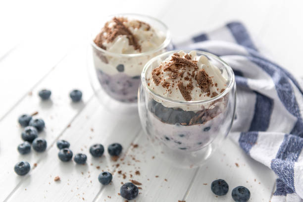 Dessert from yogurt with blueberries and chocolate on a white wooden background