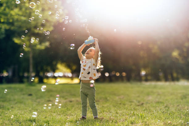 istock Young Girl Having Fun In the Park Making and Bursting Bubbles 1404530033