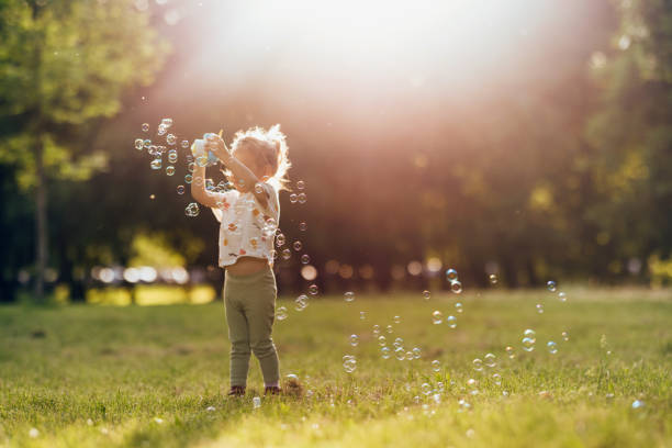 istock Young Girl Having Fun In the Park Making and Bursting Bubbles 1404530038