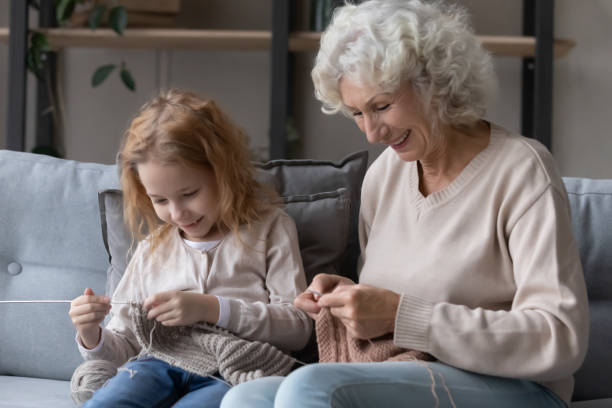 niño pequeño feliz aprendiendo a tejer con la abuela vieja. - tejidos a crochet gratis fotografías e imágenes de stock