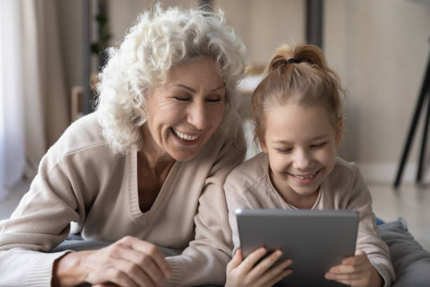 istock Overjoyed old granny playing touchpad with small kid. 1404531510