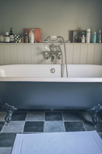 Woman taking bubble bath in vintage bathtub with brass faucet