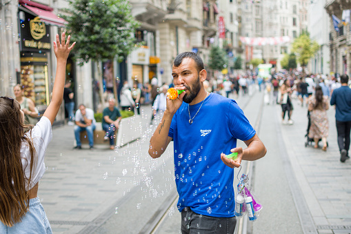 Istanbul, Turkey - June 20, 2022: Little girl playing with bubble on Istiklal Avenue in Istanbul, Turkey