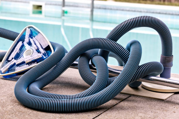 istock Pool vacuum cleaner and hose sits beside residential pool 1404533793
