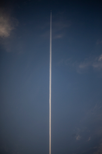 Trace of plane in sky. White line in blue sky. Vertical frame of oxygen footprint.