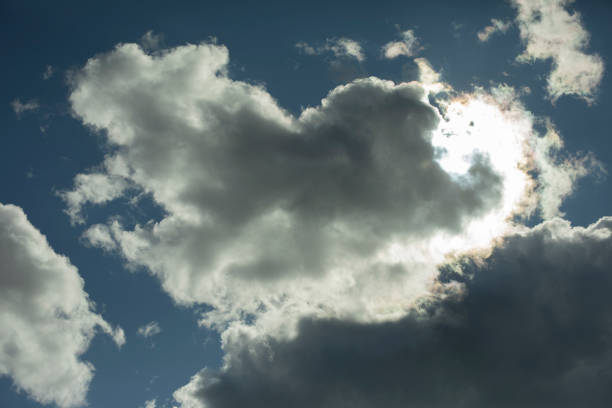 The clouds that cover the sky and the sun behind the clouds