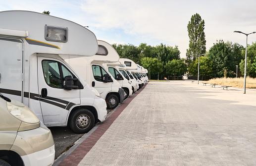 Group of motorhomes in a parking lot, waiting to be used during the vacations.