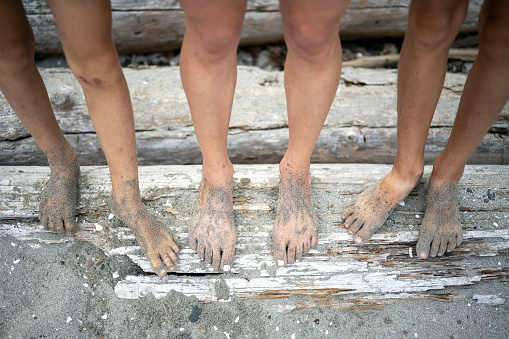 Details of a beach vacation. Feet covered in sand at the beach.