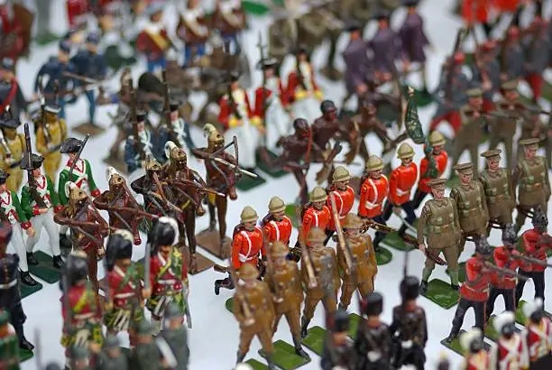 Rows of antique toy soldiers on a white tablecloth.  Limited depth of field.