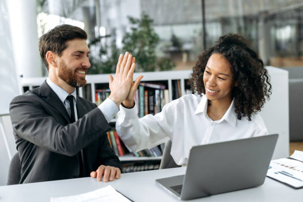 istock Good deal. Great job. Two successful multi-ethnic colleagues work in a modern office on a project, give each other five, rejoice at a successful deal, good profit, a successful startup, smiling 1404543965
