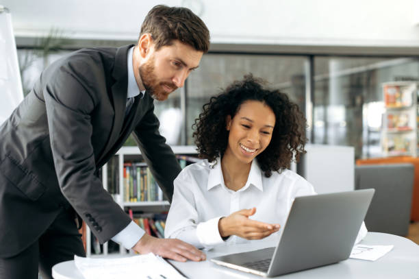 istock Brainstorm. Two successful business partners of different nationalities working together on a project, develop a startup, in modern office, using laptop,thinking together,analyzing financial documents 1404543989
