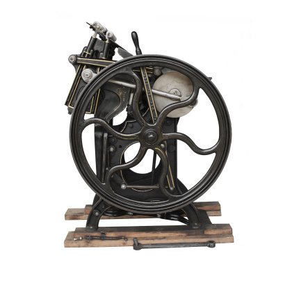 1901 black printing press showing the flywheel and gold detailing isolated against a white background