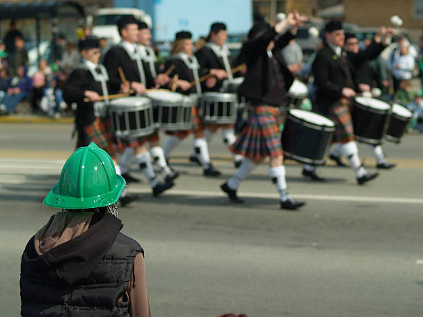 person in green hat watching drummers walk by in the parade - optocht stockfoto's en -beelden