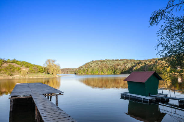 Panorama of Sotsko Jezero, or lake Sot, in Fruska Gora, in Serbia, Europe, in summer, at dusk, with a holiday cabin and a pontoon over the water. it is a major natural landmark of Vojvodina. stock photo