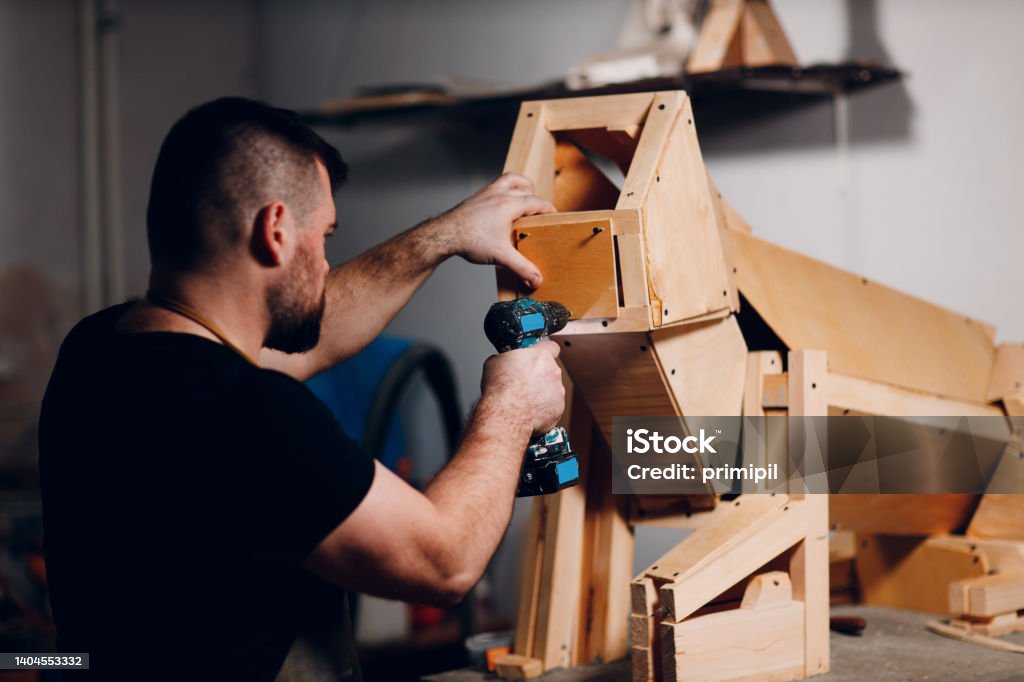 Artisan craftsman carpenter sculptor frame wooden create carcass framework. Artisan craftsman carpenter sculptor frame wooden create carcass framework. Wooden board, plywood and screwdriver Molding a Shape Stock Photo