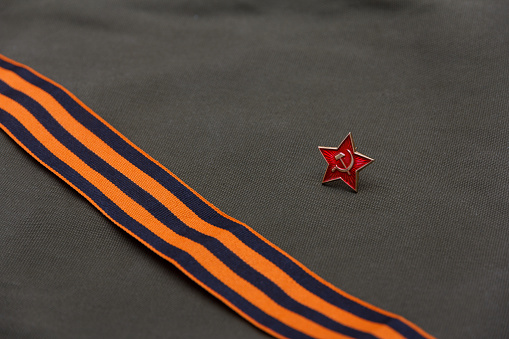 Soviet red star badge on the background of the St. George ribbon and army fabric.