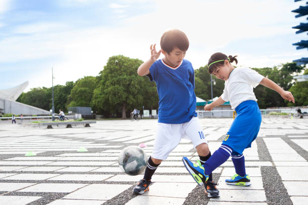 サッカーをしている小学生の男の子と女の子。 - 子供サッカー ストックフォトと画像
