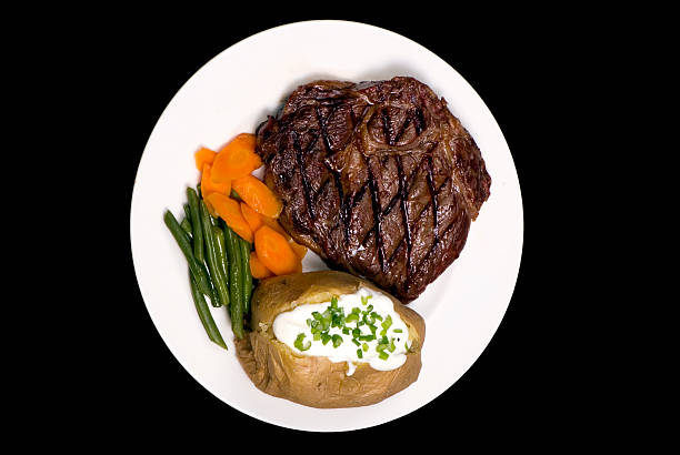 A thick juicy Rib Eye steak dinner with a baked potato