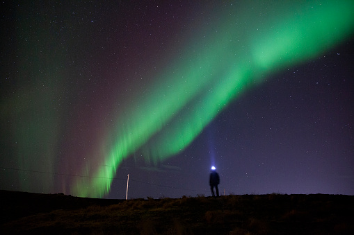 Magical Aurora borealis above a silhouetted man in Iceland